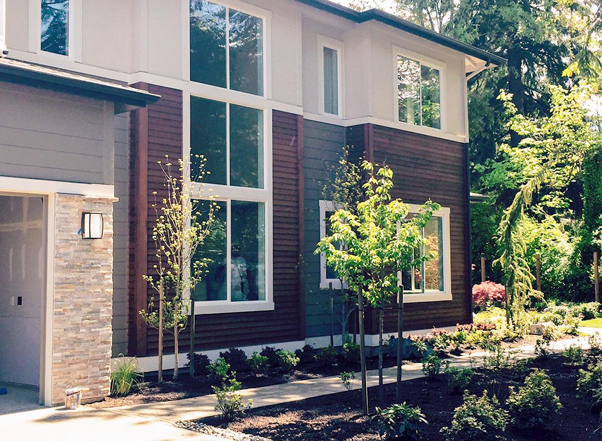 House plan exterior of a two-story modern home with stacked stone accents, a prominent two-story window, and horizontal siding.