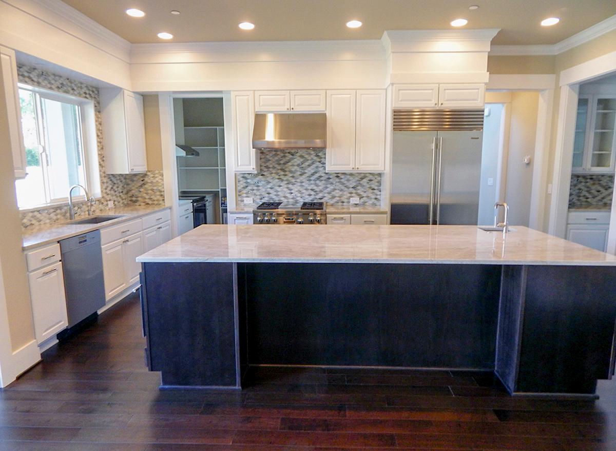 Kitchen with white cabinetry, granite countertops, stainless steel appliances, large island, and mosaic tile backsplash.