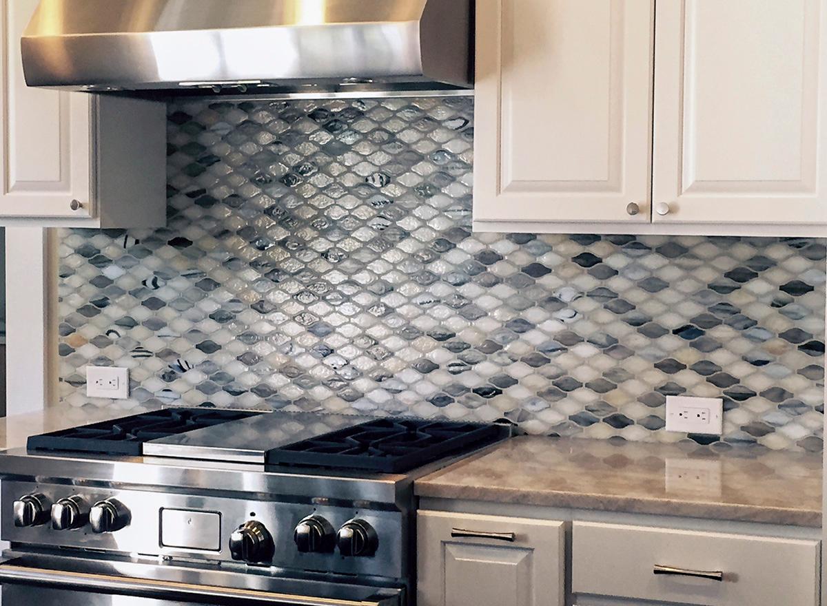 Kitchen detail with stainless steel range, mosaic tile backsplash, and white cabinetry.