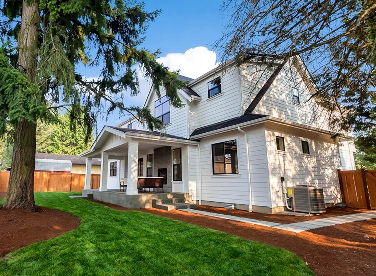 Two-story modern farmhouse exterior with covered front porch, large gables, and prominent windows.