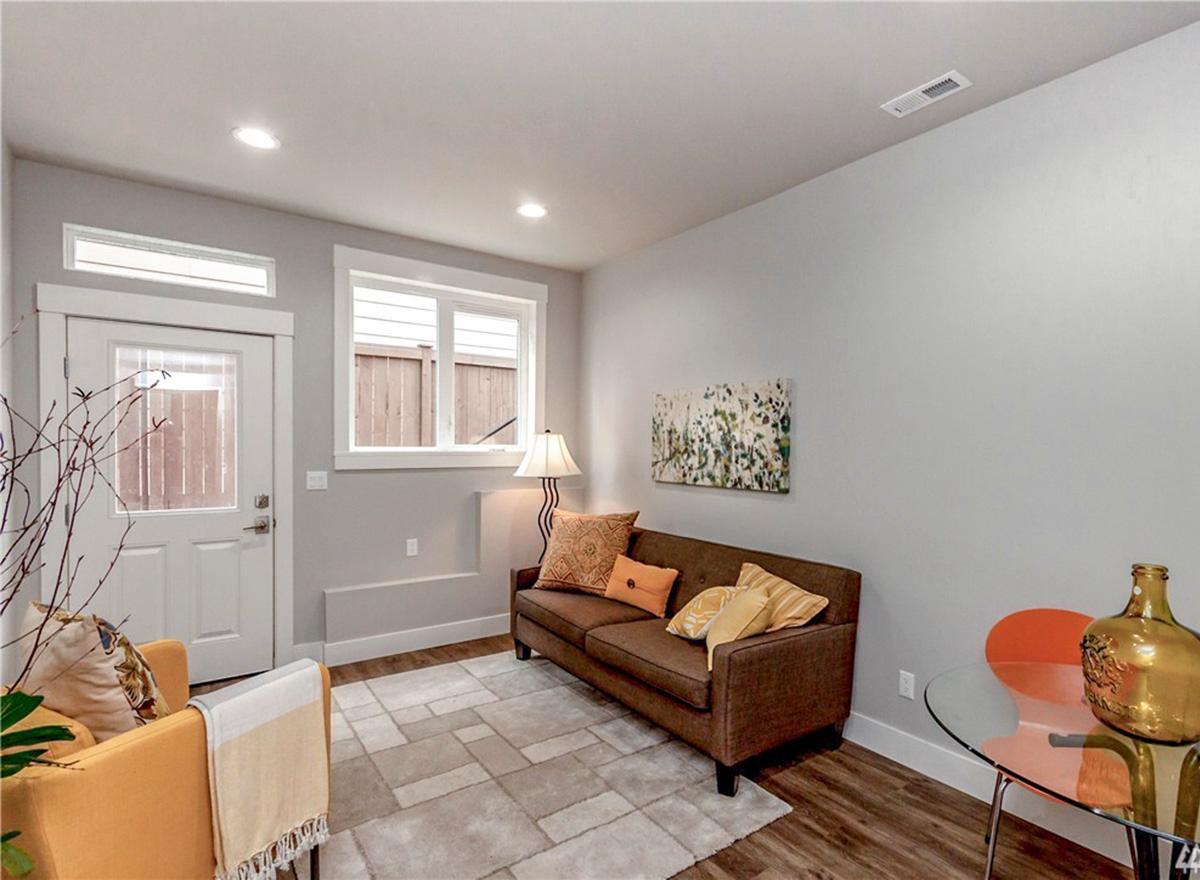 Living area with sofa, armchair, glass-top table, and door with transom window.