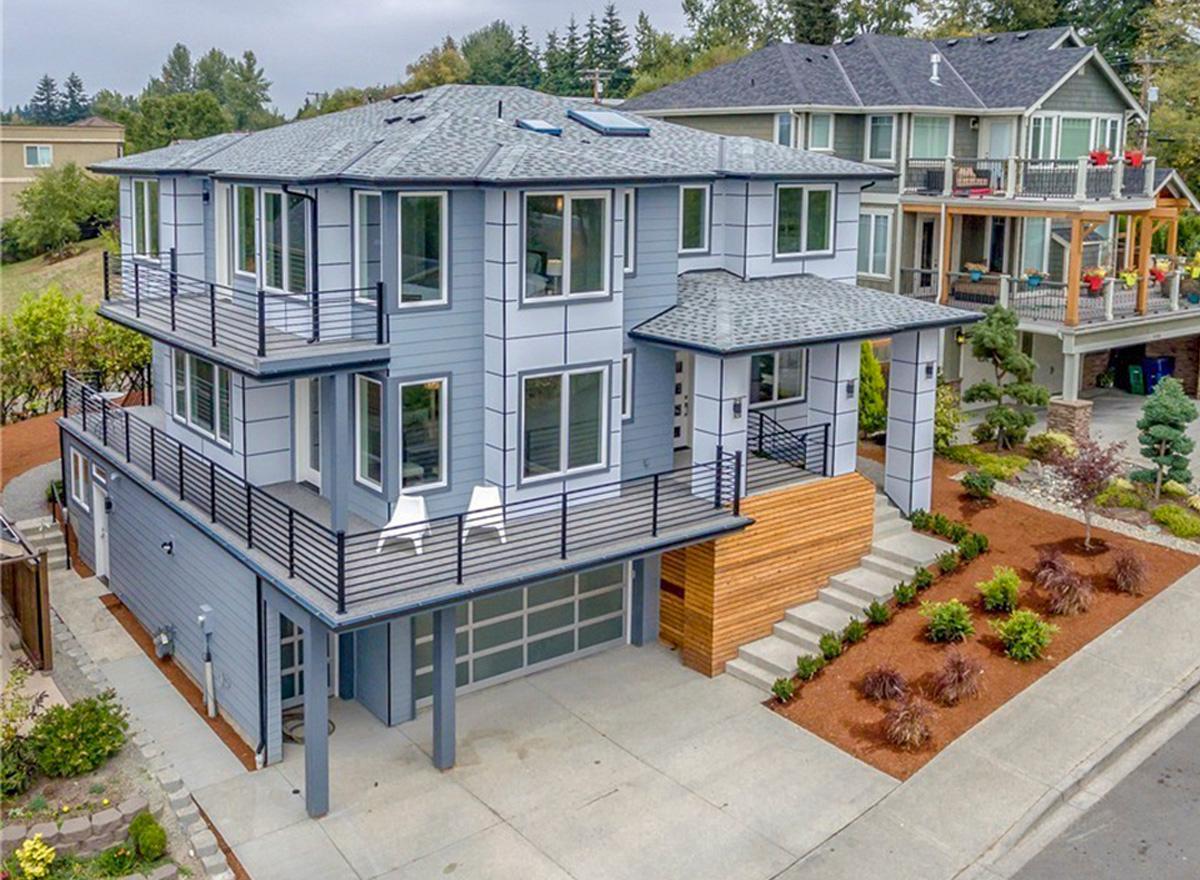 Modern house plan exterior, three stories, with multiple balconies, contemporary siding, and a multi-pane garage door.