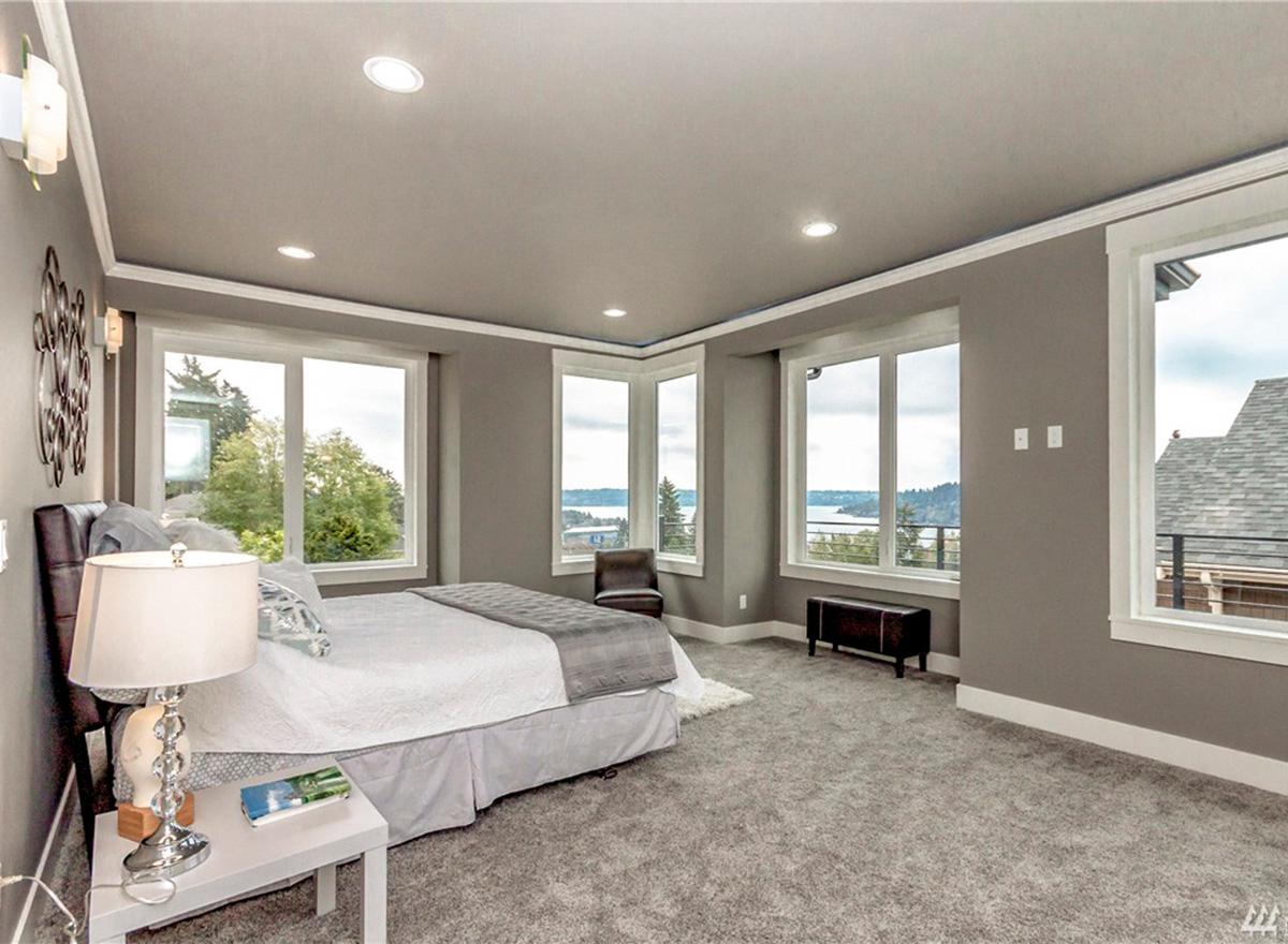 Primary bedroom with large windows offering panoramic views, recessed lighting, and crown molding.
