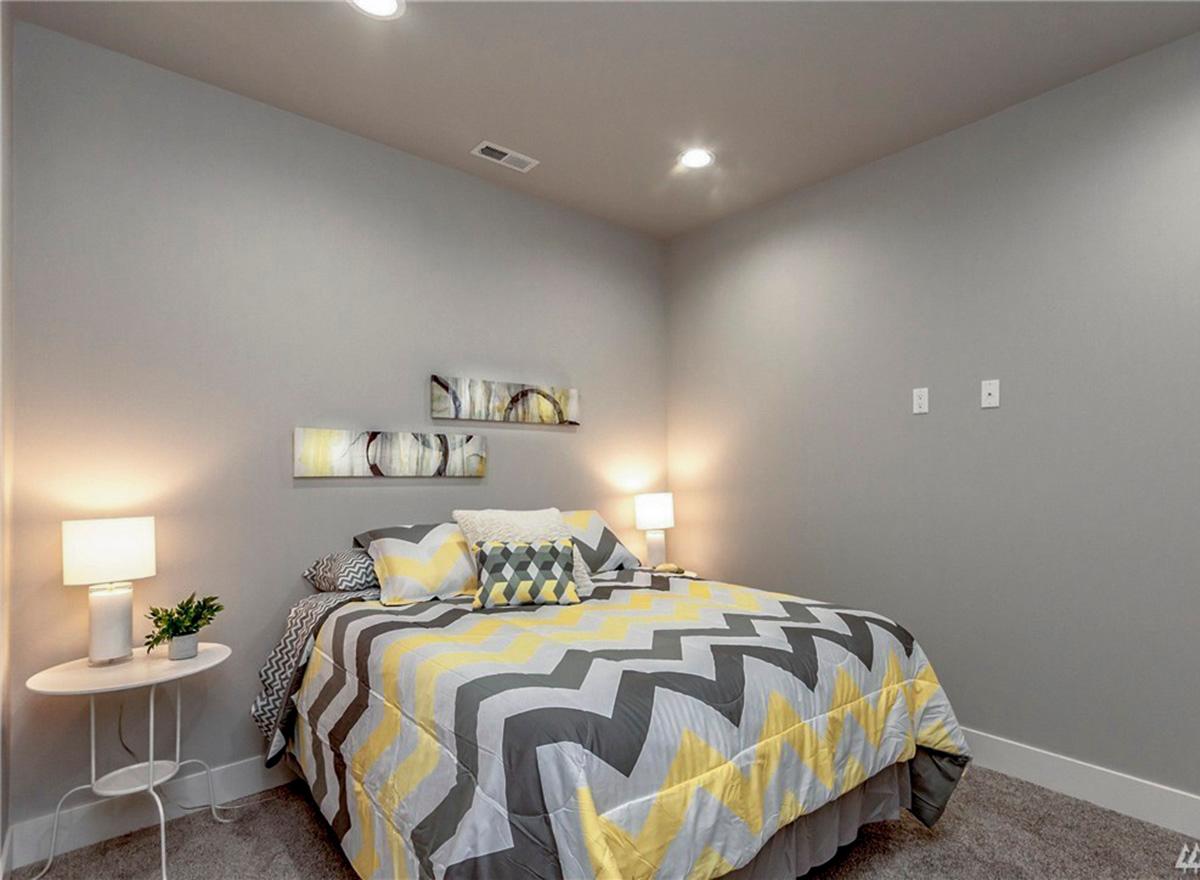 Bedroom with bed, side table, recessed lighting, and wall art.