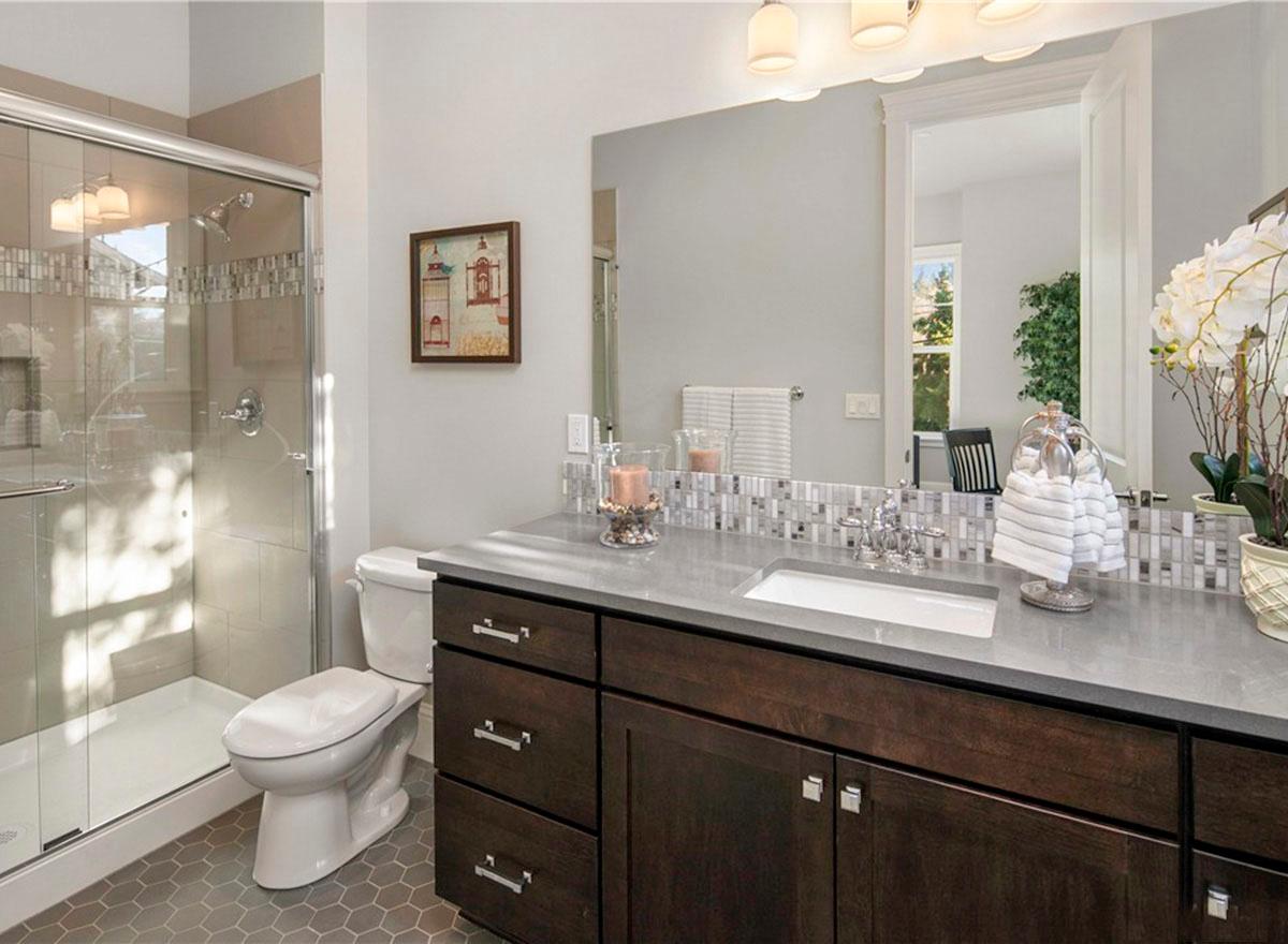 Bathroom with glass-enclosed shower, vanity with double sinks and dark wood cabinets, and hexagonal tile flooring.