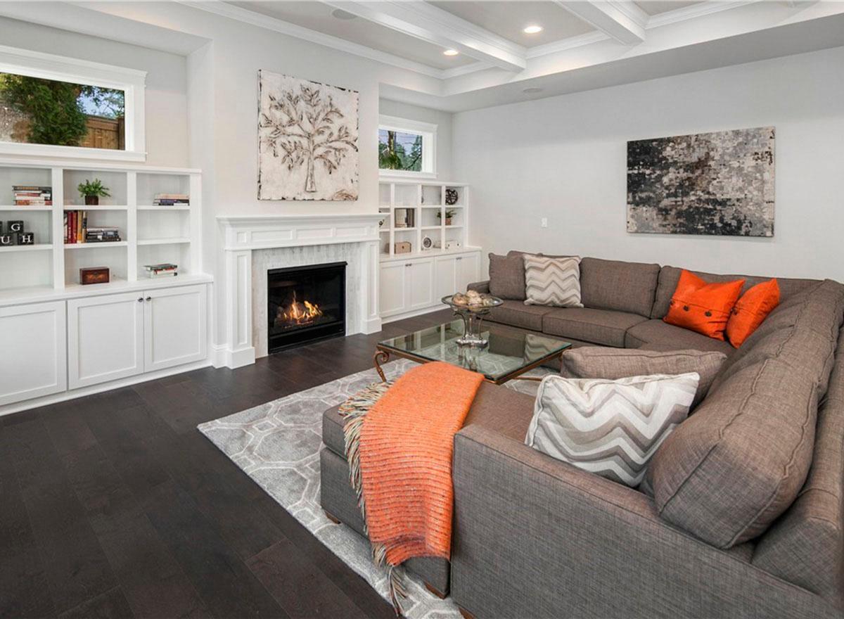 Living room with coffered ceiling, fireplace, built-in shelving, sectional sofa, and glass coffee table.