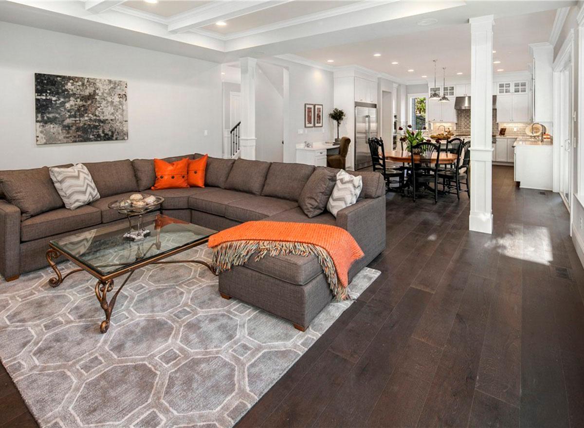 Open concept living area with large sectional sofa, coffee table, dining set, and kitchen visible.