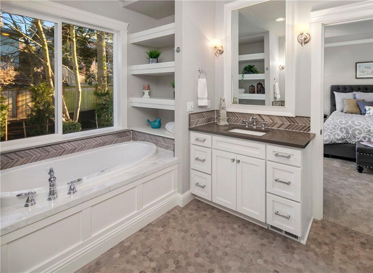 Bathroom with soaking tub, vanity with undermount sink, and a doorway to bedroom. Built-in shelving displays decorative items.