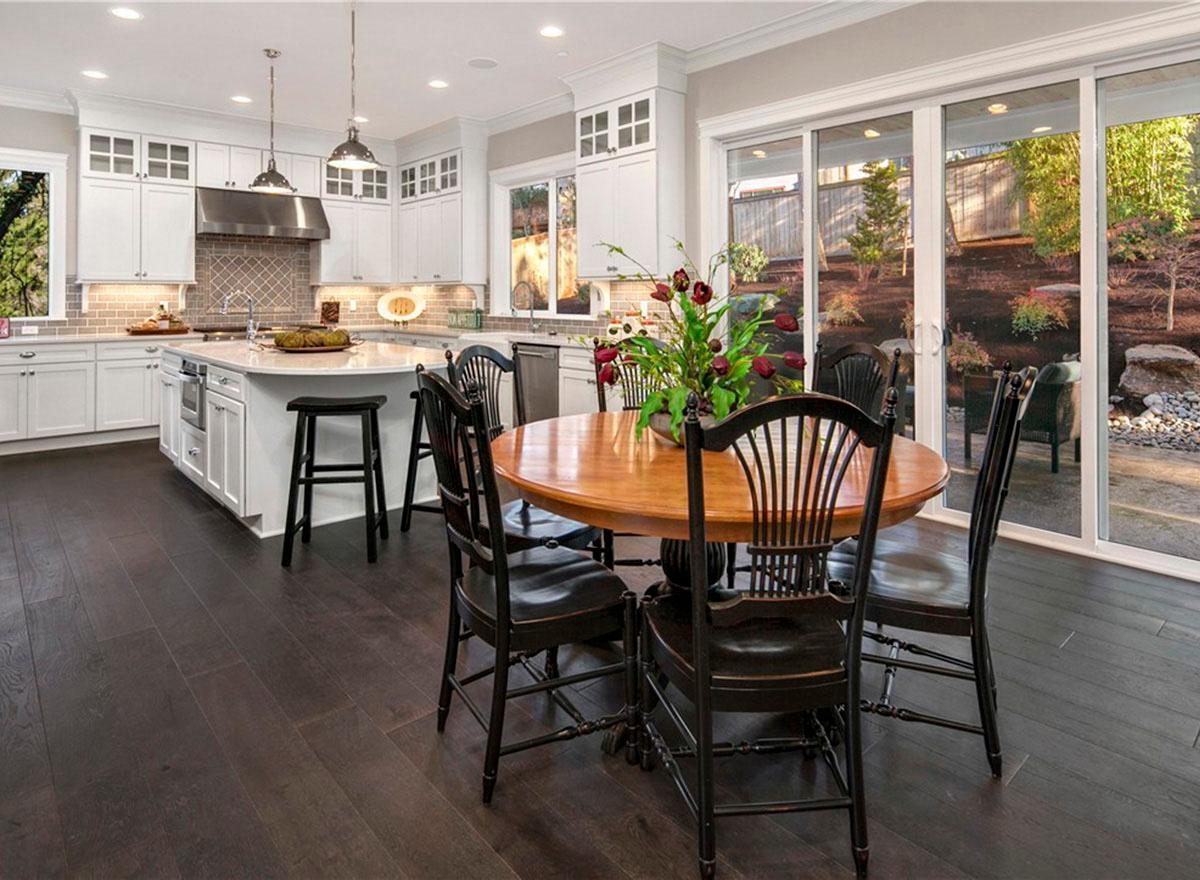 Kitchen and dining area with island, pendant lights, and large sliding glass doors opening to a landscaped yard.