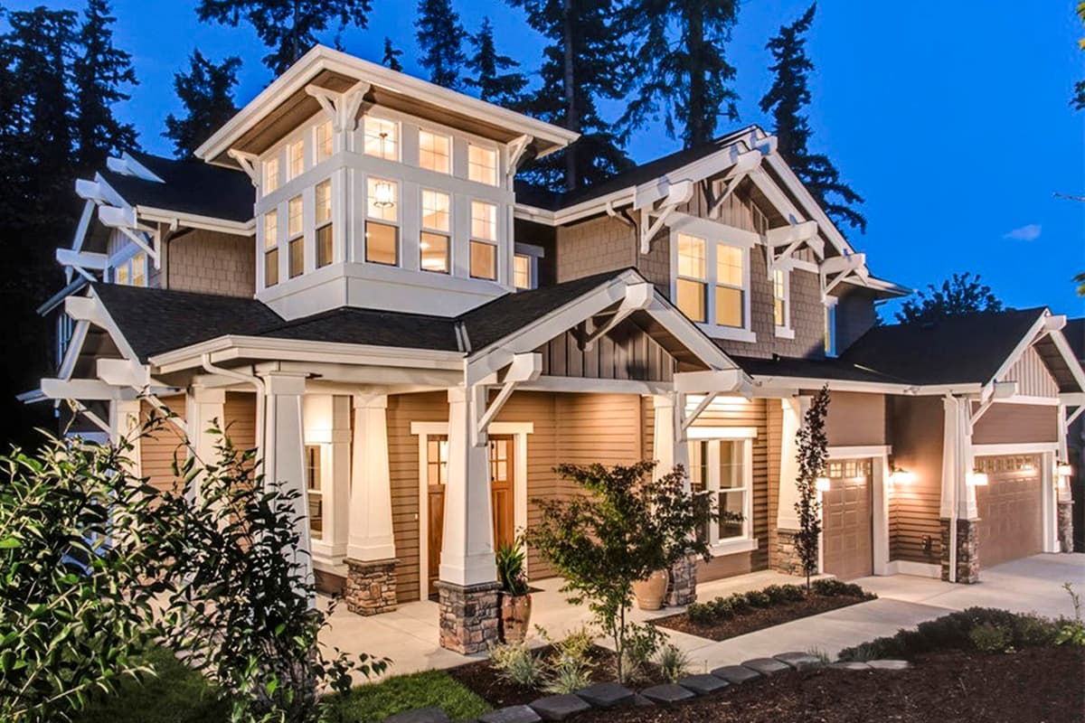 House plan exterior. Two-story Craftsman home with a front porch, gables, and multi-paned windows. Features an attached garage and bracketed eaves.