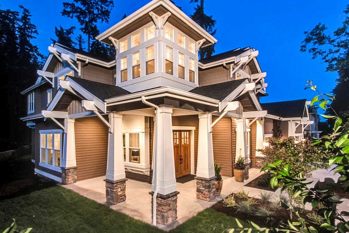 Craftsman style house plan exterior with multiple gables, a covered porch with stone-accented columns, and a prominent central dormer.
