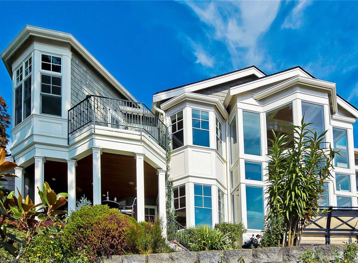 House plan exterior with bay windows, gabled dormer, balcony, and prominent columns supporting upper level.
