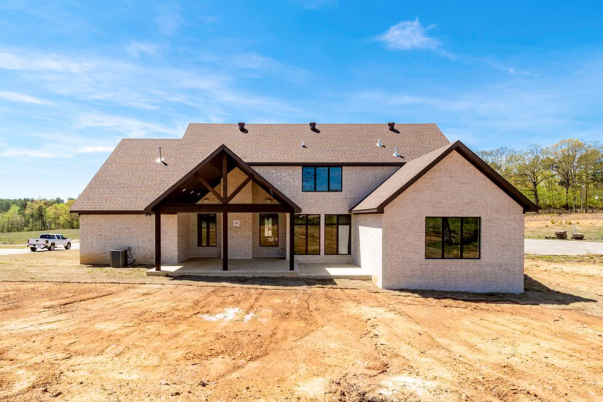 House plan exterior with white brick, gabled roof, exposed rafter tails, and covered patio.