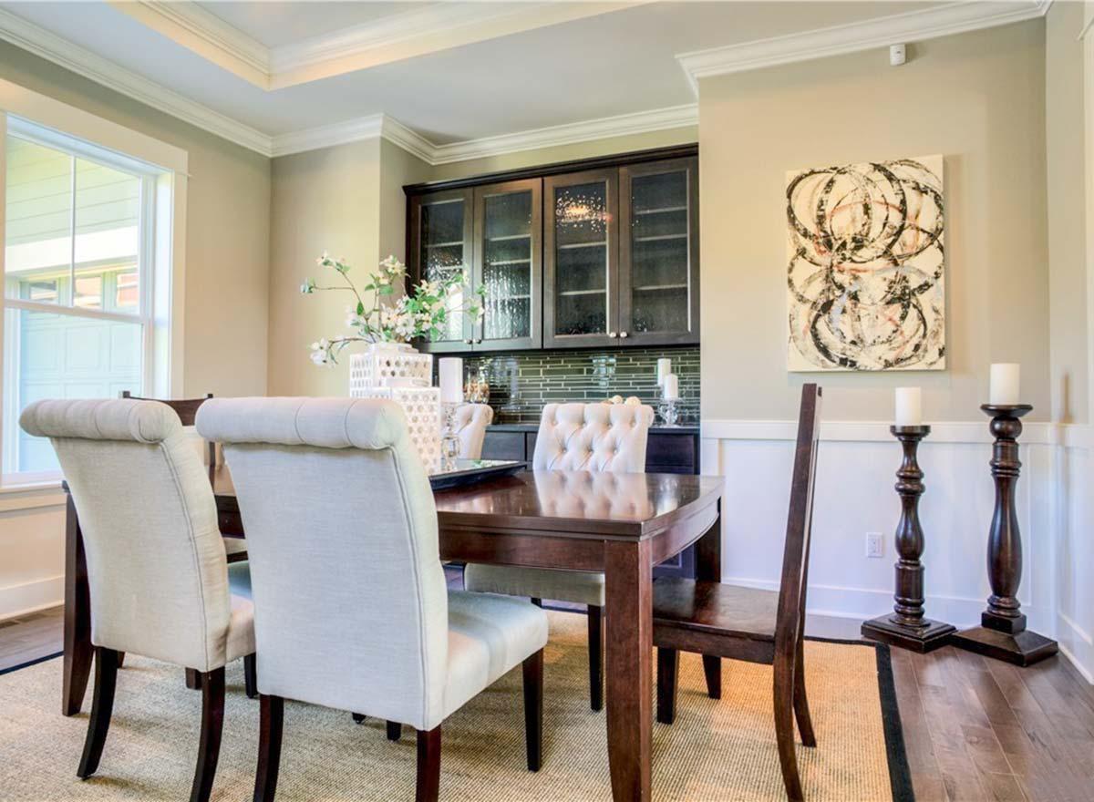 Dining room with dark wood table, upholstered chairs, glass-front cabinets, and wall art.