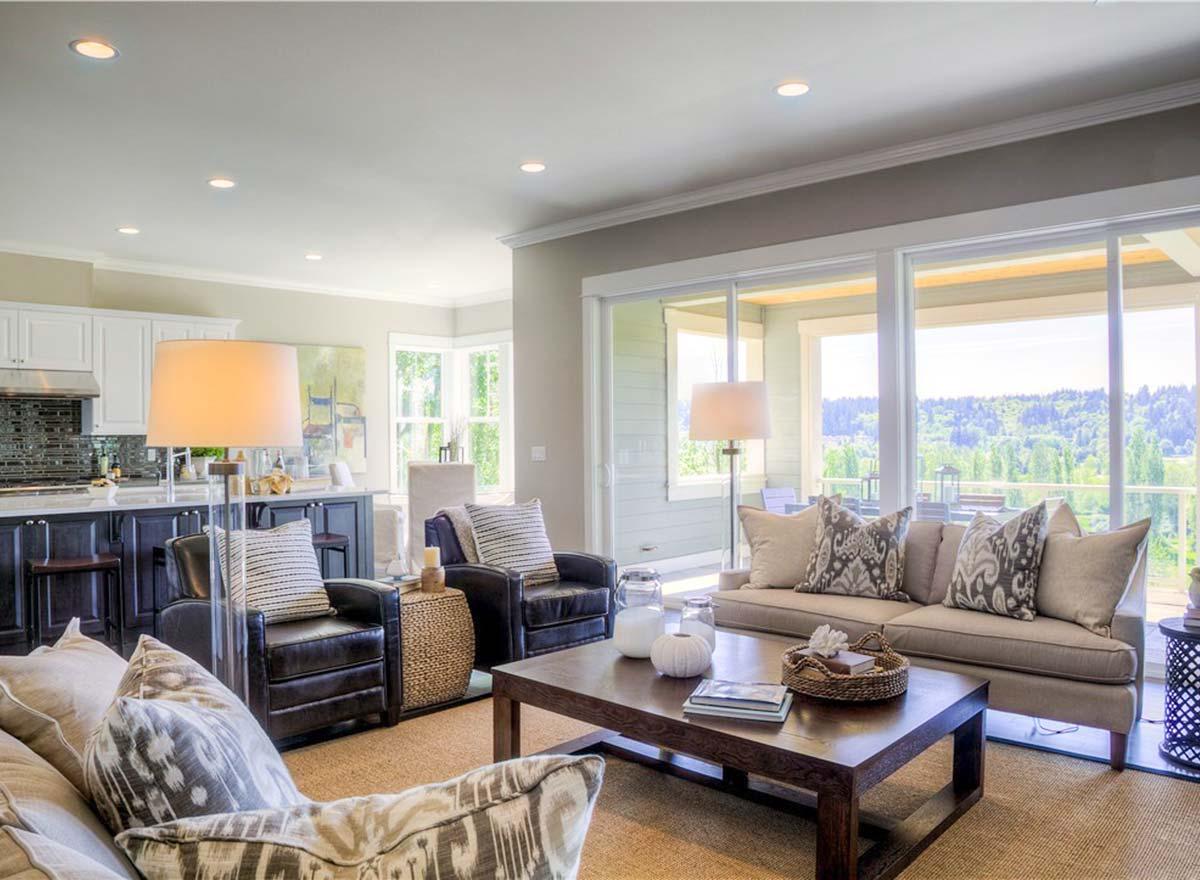Living room interior with dark leather chairs, a neutral sofa, and large sliding glass doors opening to a covered patio with scenic views.