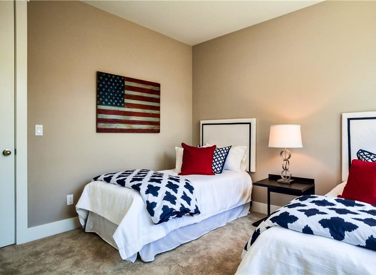 Bedroom interior with two twin beds, navy and white patterned bedding, and American flag wall art.
