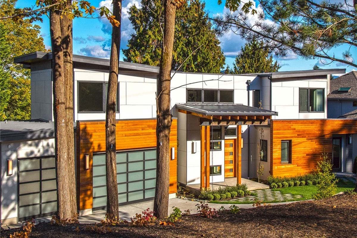 Modern house plan exterior with wood siding, flat roof, multi-story windows, and a cantilevered porch.