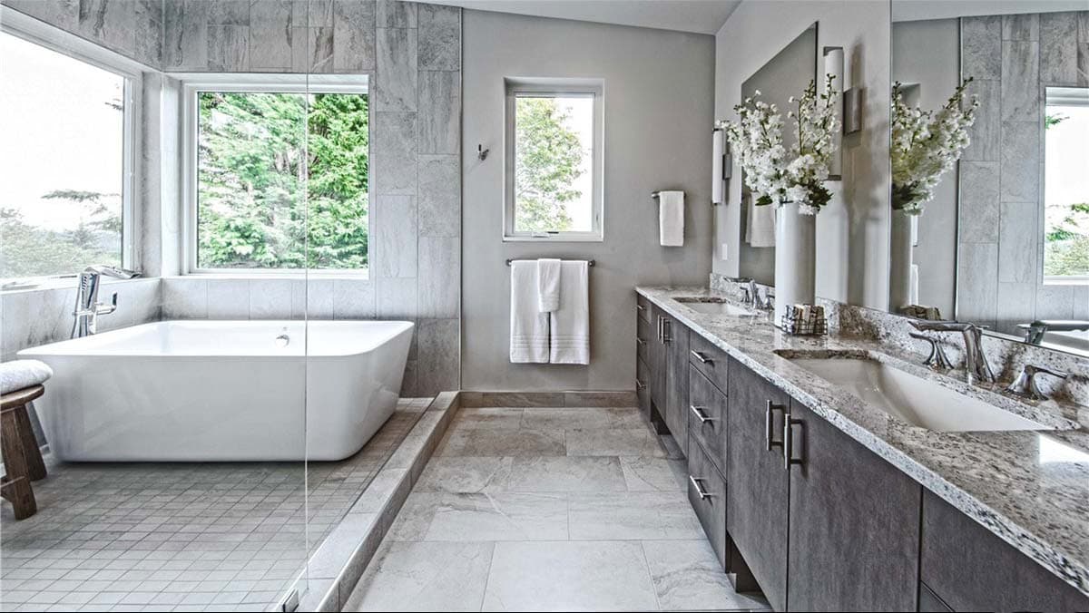 Modern bathroom with freestanding tub, dual vanity with granite countertops, and large windows.