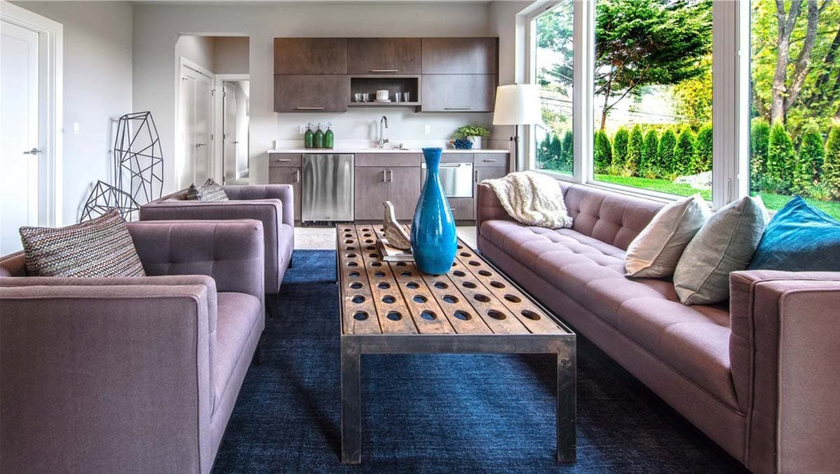 Living room with two sofas, a wet bar, and large windows overlooking a garden.