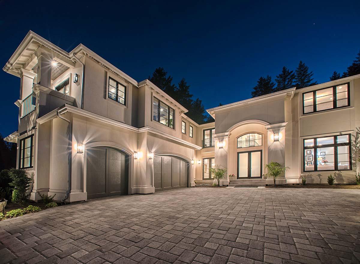 Modern house plan exterior with three-car garage, arched entry, and upper-level balcony.