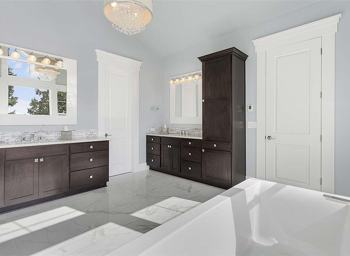 Bathroom with double vanity, dark wood cabinets, vaulted ceiling, and freestanding tub.