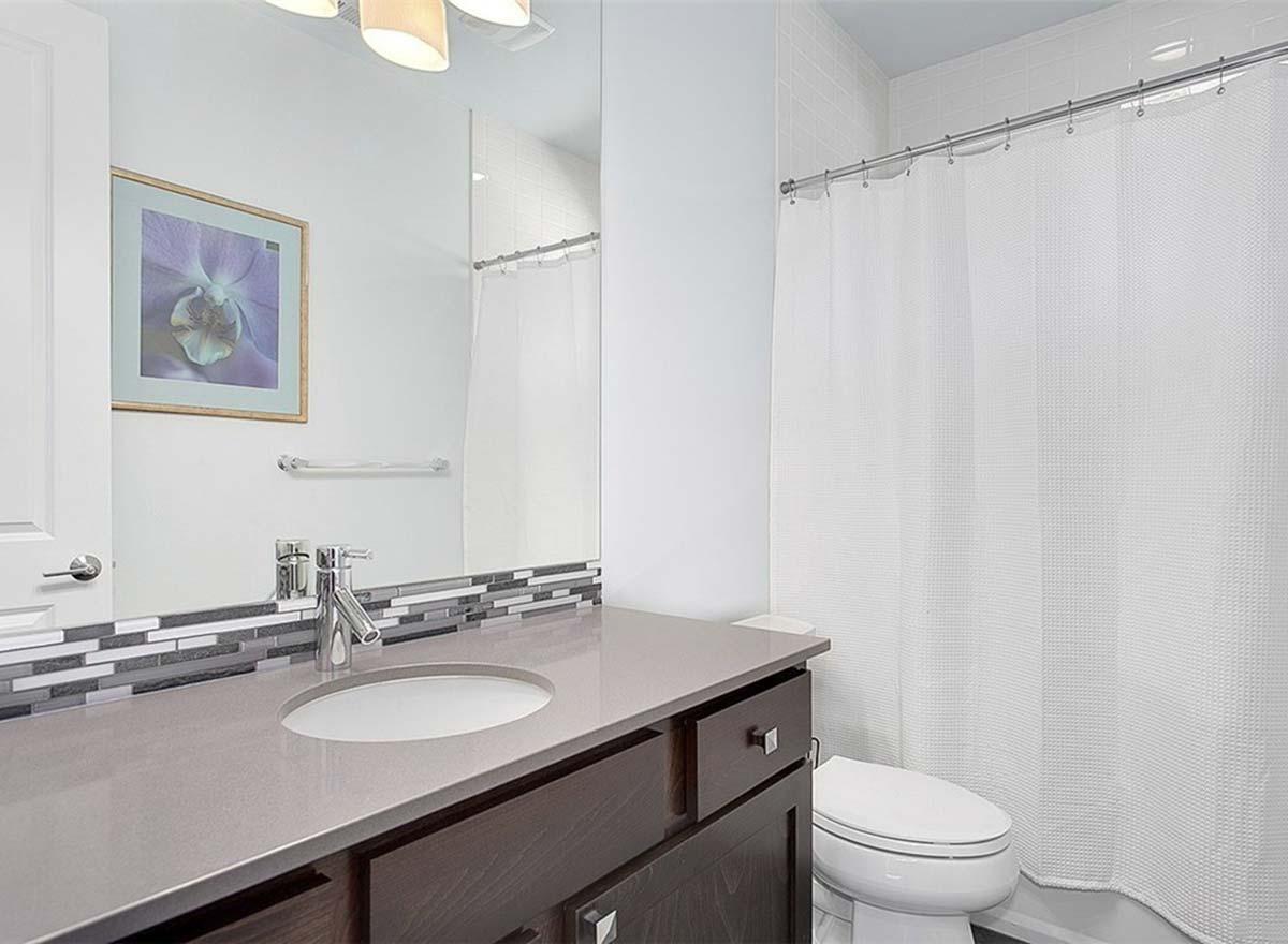 Bathroom interior with vanity, sink, toilet, and shower with white curtain.