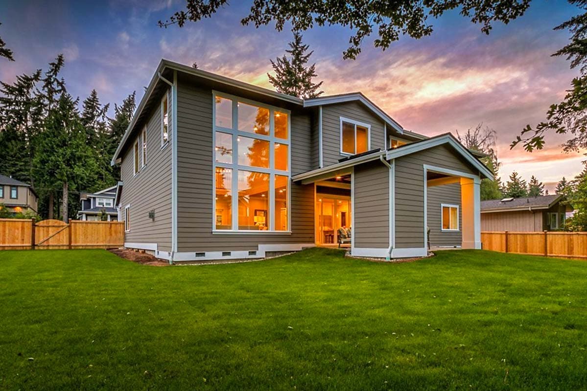 House plan exterior with two stories, vertical siding, a covered porch, and a large multi-pane window wall.