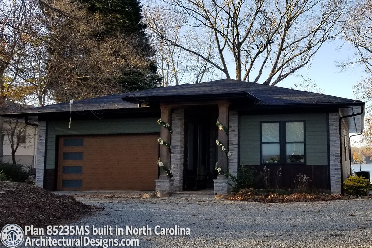 Modern house plan exterior with a single story, a covered entry with stone columns, and a wood-look garage door.