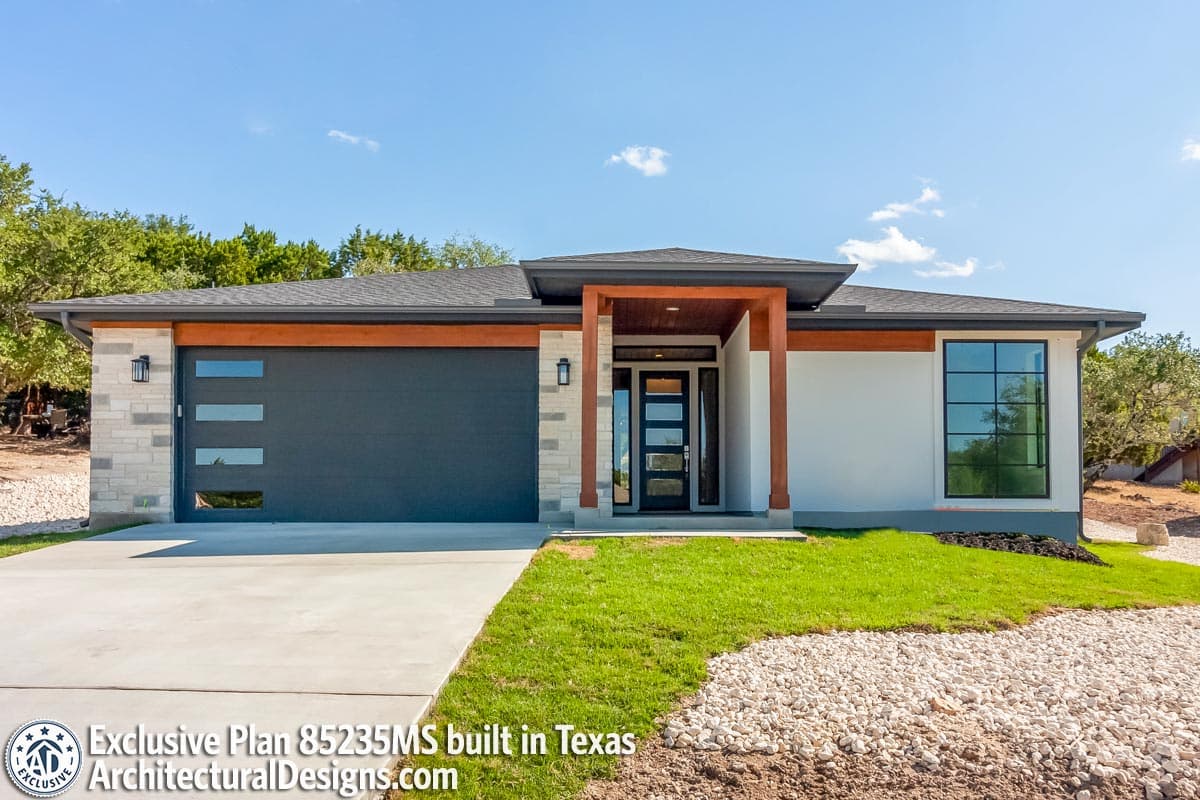 Modern house plan exterior with a dark garage door, contemporary entry, and large grid window. One story.