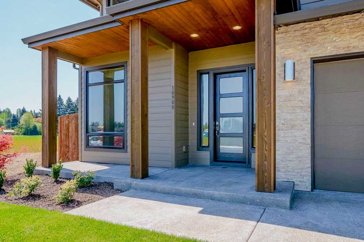 Modern house exterior with wood soffits, contemporary door, stone accent, and large windows. House plan.