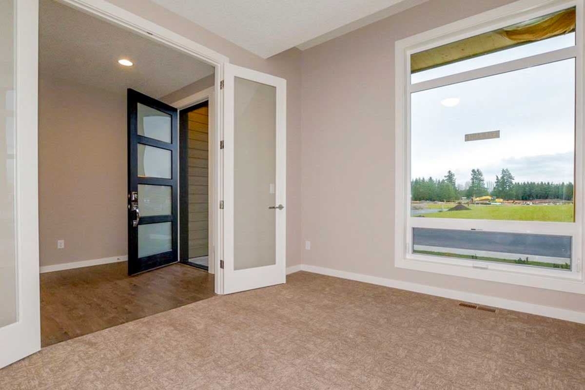 Interior view of room with large window, wood floor, and open doorway to hallway with modern black door.