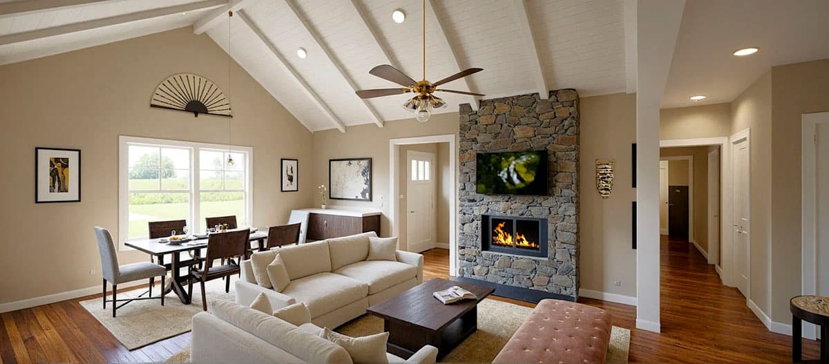Living room with vaulted beamed ceiling, stone fireplace, dining area with large windows, and hardwood floors.