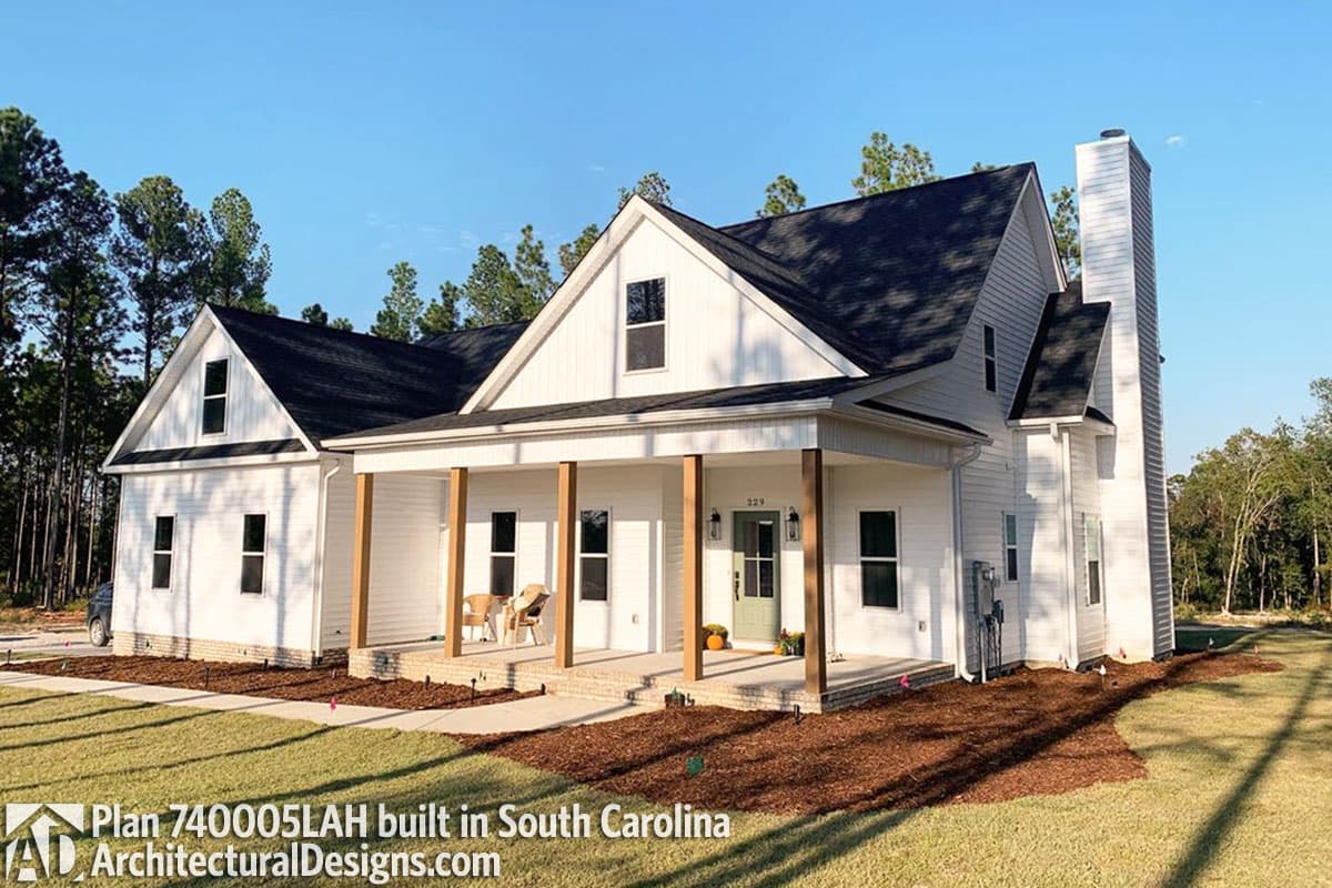 House plan exterior: Modern Farmhouse style, 1.5 stories, with a prominent covered porch, gabled dormers, and a tall brick chimney.