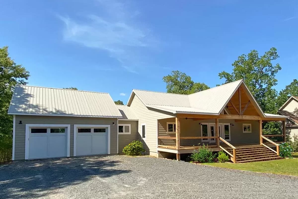 House plan exterior with metal roof, two-car garage, and a covered porch with a wood-framed gable entrance.