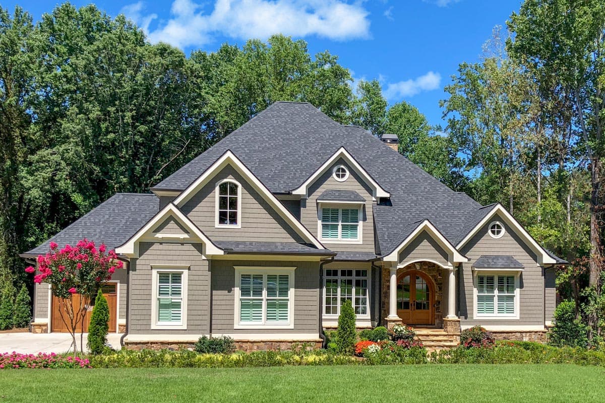 House plan exterior. Two-story home with multiple gables, arched entry, and dormers. The house features a dark gray roofline and siding.