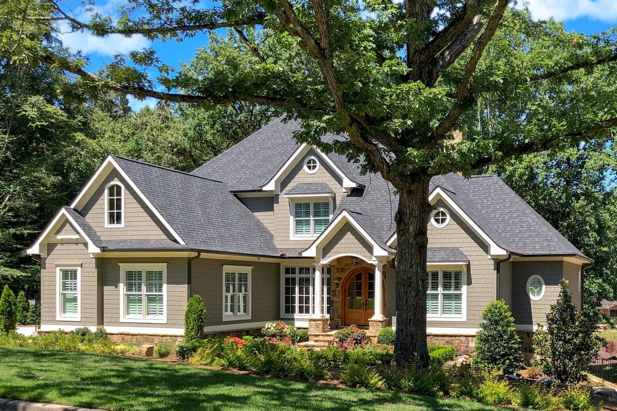 House plan exterior: Modern Farmhouse style, two stories, with arched dormers, gabled rooflines, and stone-accented entryway.