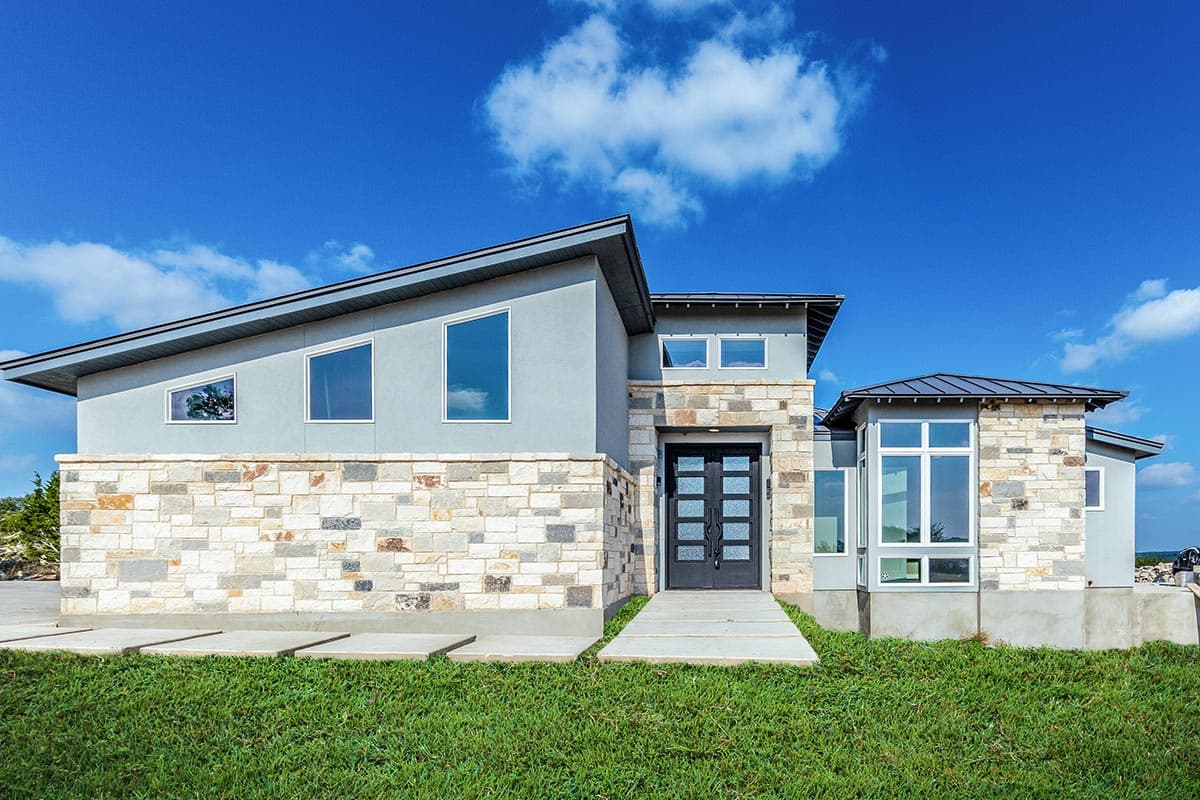 House plan exterior. Modern style, single story. Features include stone veneer, flat roof, and large windows. Includes side entry and walkway.