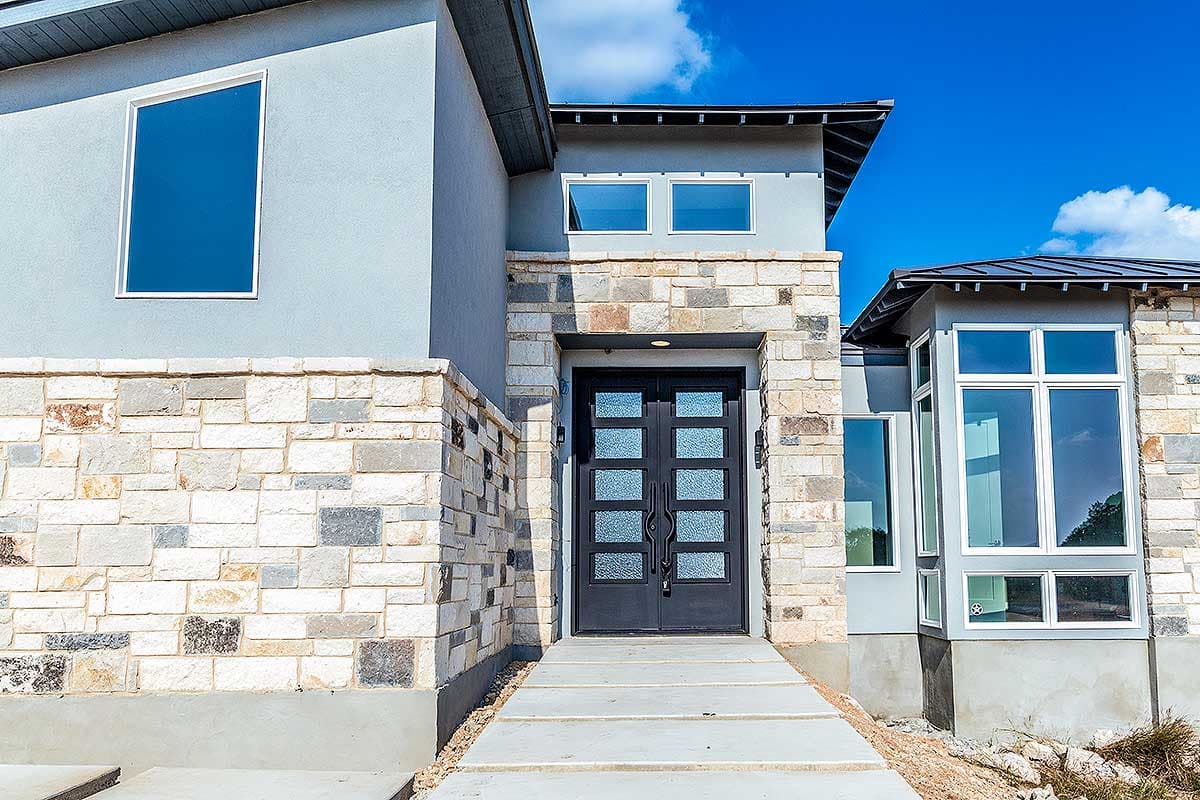 Modern house plan exterior with stacked stone accents, double entry doors, and multiple window styles including a bay window.