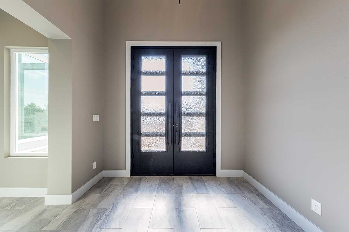 Interior view of double entry doors with frosted glass panes and a large window to the left.