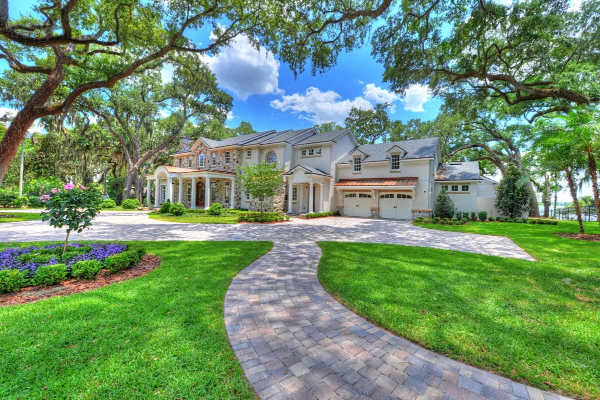House plan exterior: Large two-story home with stone accents, portico, and attached three-car garage.
