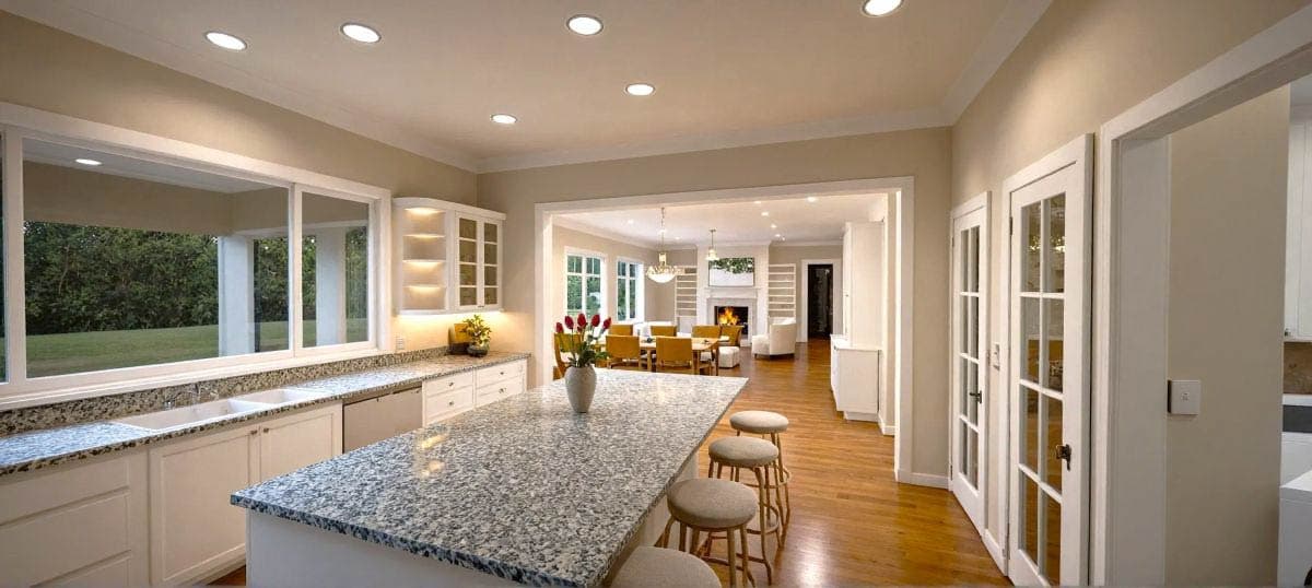 Kitchen with large island, granite countertops, and a pass-through to a dining room with a fireplace.