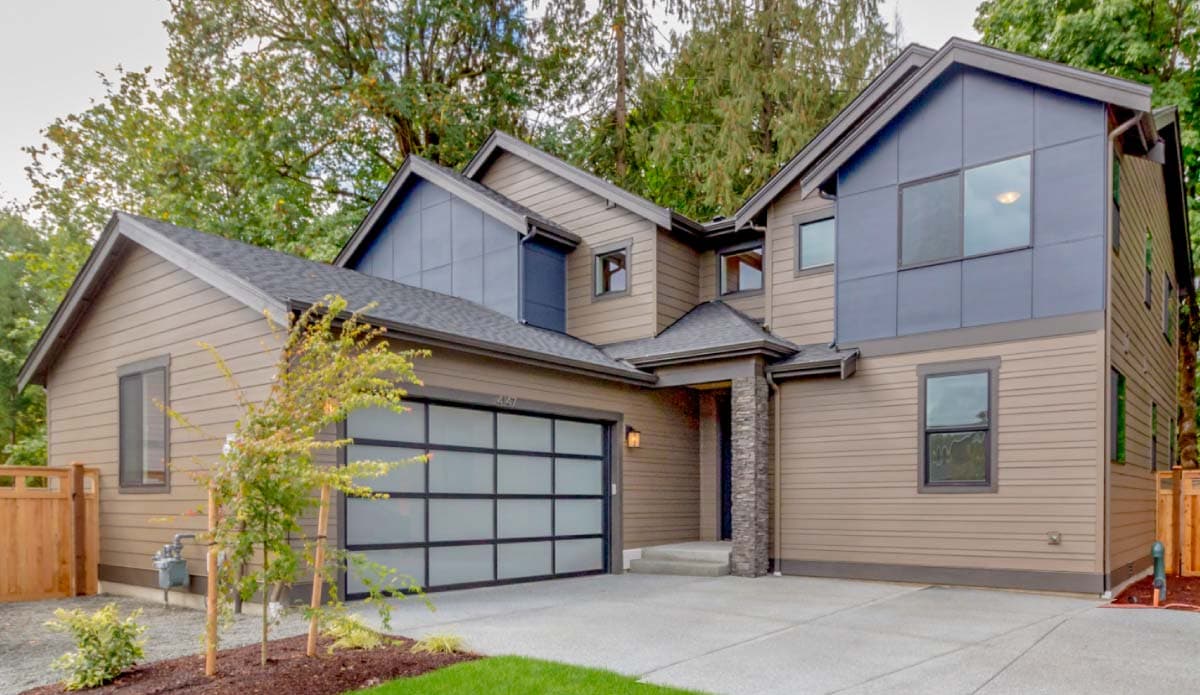 House plan exterior with modern design, two stories, and a glass-paneled garage door. Features a covered entry and multiple gabled roof sections.