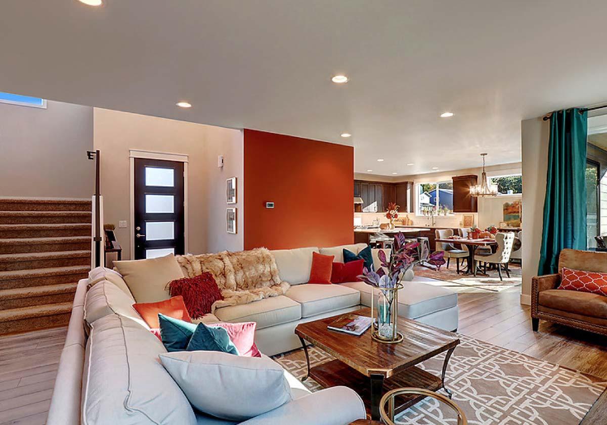 Interior view of a living room and kitchen area with sectional sofa, fireplace, dining table, and dark wood cabinets.