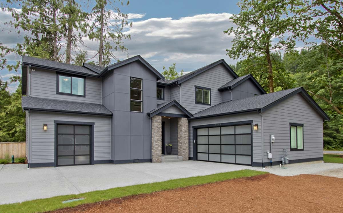House plan exterior. Two-story modern house with a gabled roof, two-car garage, and stone entry columns.