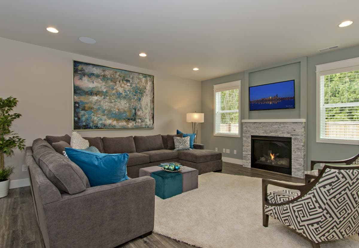 Great room with sectional sofa, fireplace, TV, and large abstract art.