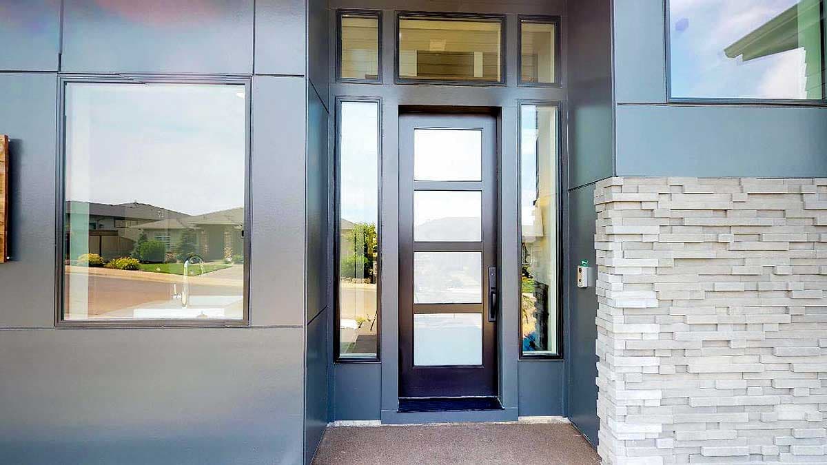 Modern house exterior with dark metal siding, a multi-panel glass door, and stacked stone accent wall.