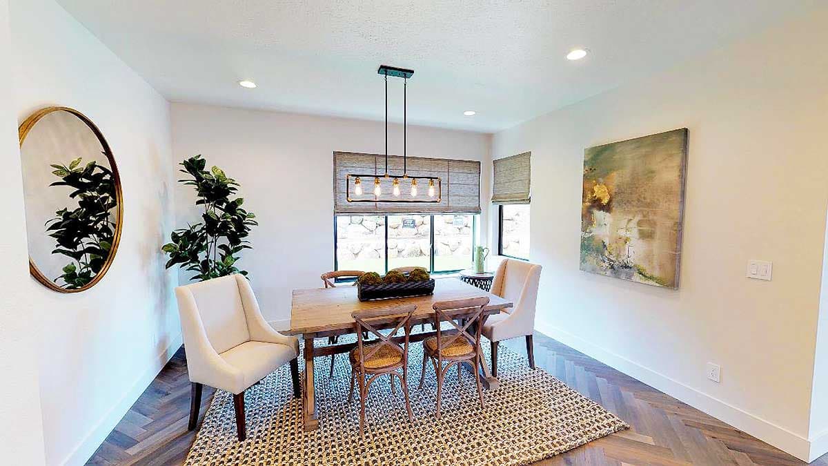 Dining room interior with wooden table, chairs, pendant light, large window, and artwork.