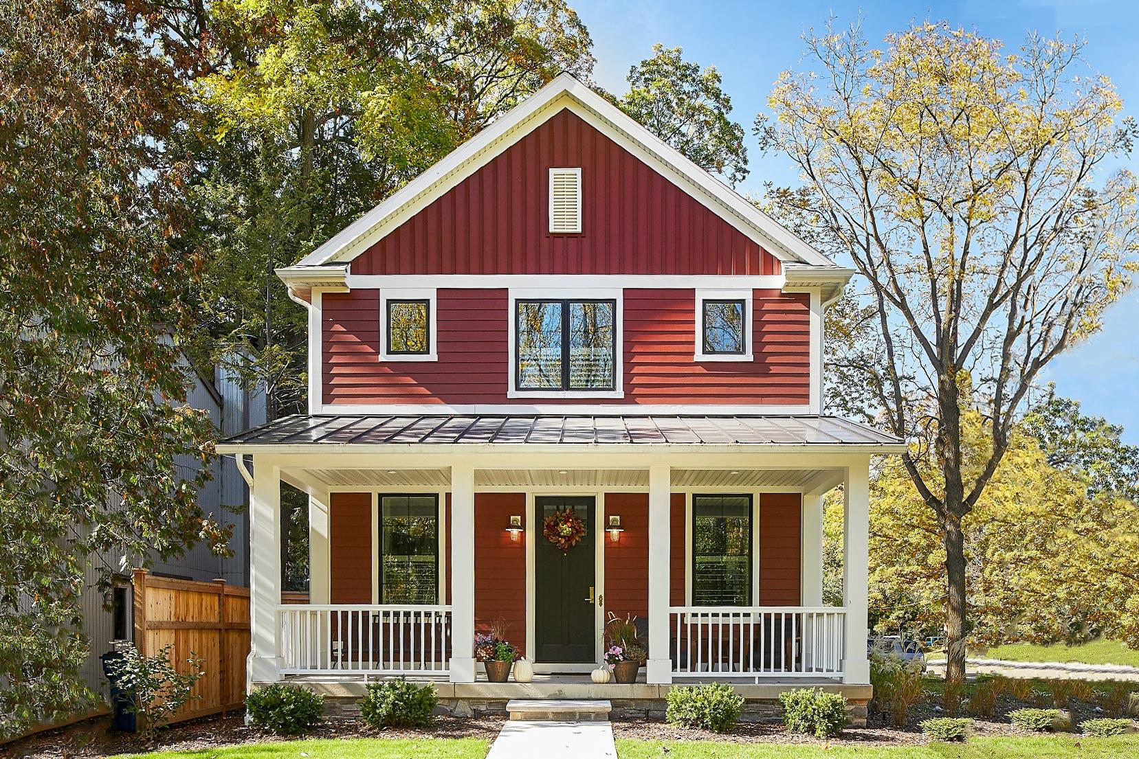 Two-story house plan exterior with front porch, gabled roof, and vertical siding. Features include multiple windows and a metal roof.