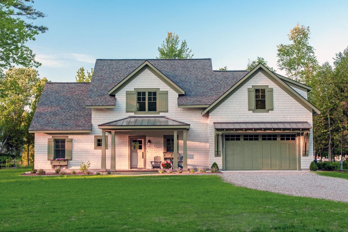 House plan exterior. Two-story Craftsman home with a front porch, gabled roofline, and garage. Features wood shake siding and shuttered windows.