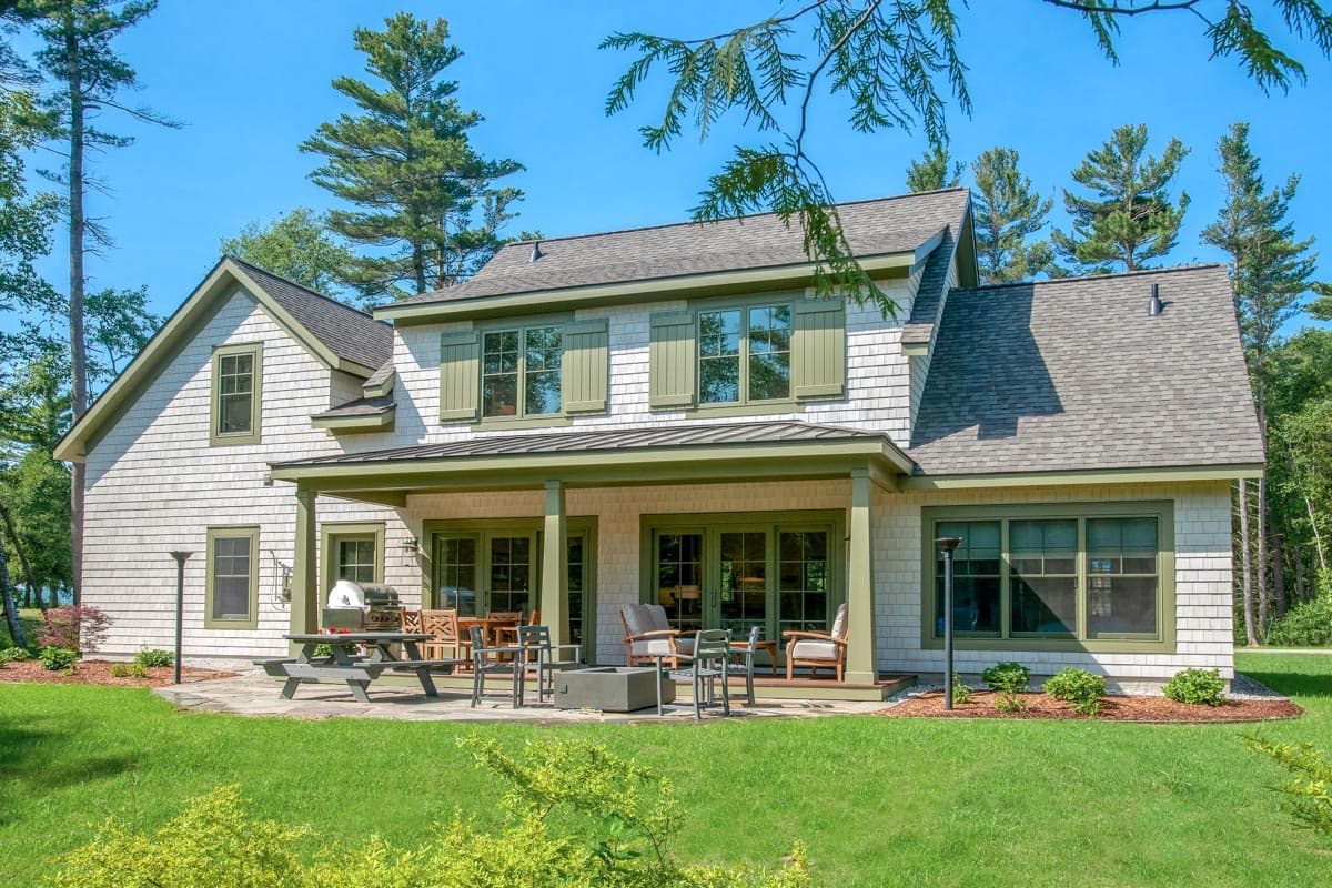 House plan exterior: Two-story Modern Farmhouse with shake siding, gabled dormers, and a covered porch with outdoor seating.